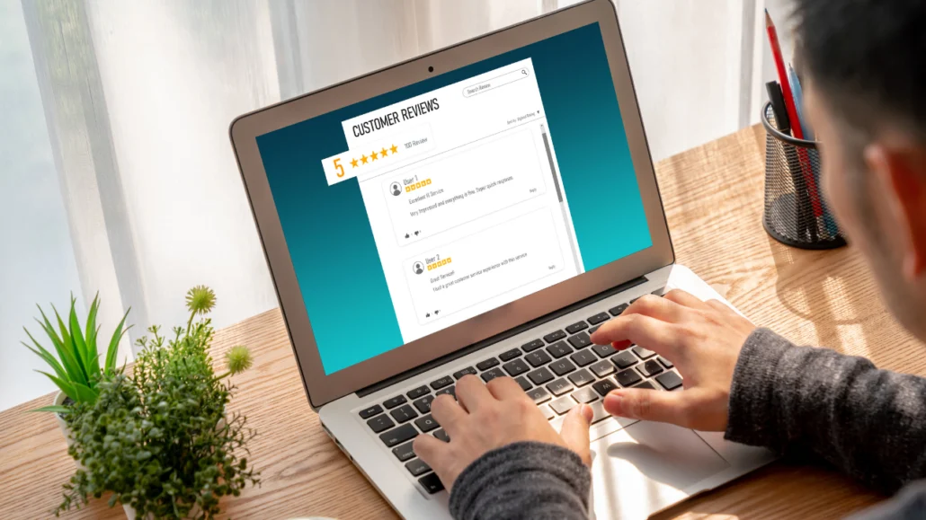 Picture of a person in front of a laptop of which screen shows a reviews platform