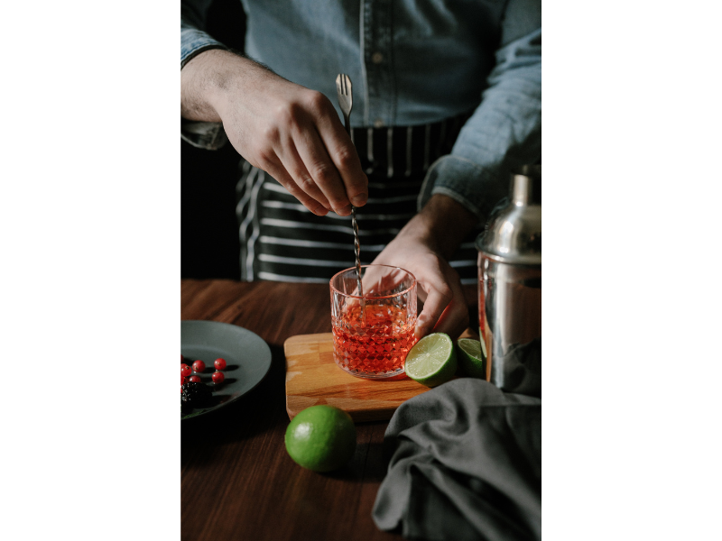 Foto van een cocktail die wordt bereid door een man in uniform